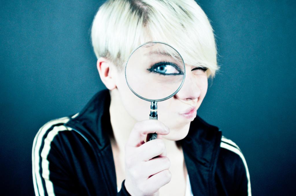 woman holding magnifying glass to her eye