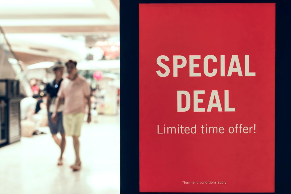 Red deal sign with walking customers