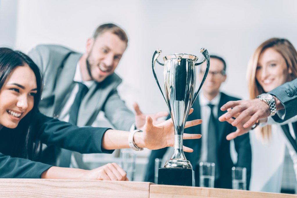 people wearing business casual reaching for trophy